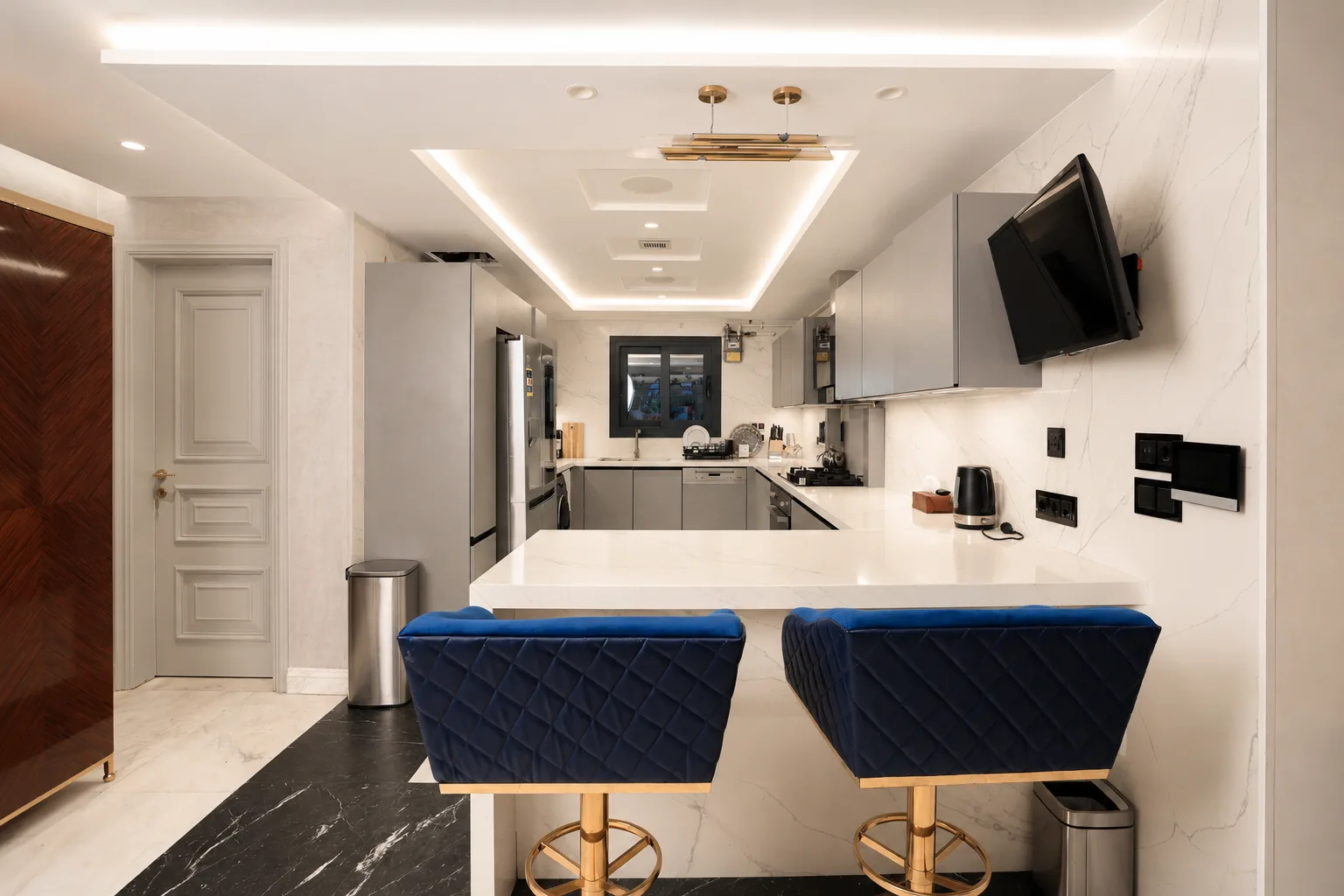 White kitchen with blue stools in the Mohandseen Apartment project in Mohandseen